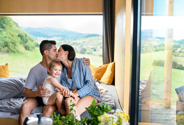 Young family with small daughter kissing indoors, weekend away in container house in countryside. - HPIF16962