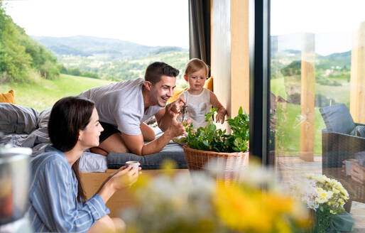 Happy young couple with small daughter indoors, weekend away in container house in countryside. - HPIF16965