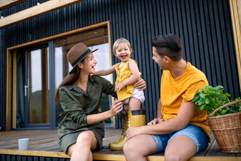 Junge Familie mit kleiner Tochter, die sich im Freien vergnügt, Wochenende im Containerhaus auf dem Lande. - HPIF16972