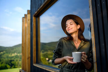 Junge Frau mit Kaffee im Freien, Wochenende im Containerhaus auf dem Lande. - HPIF16977