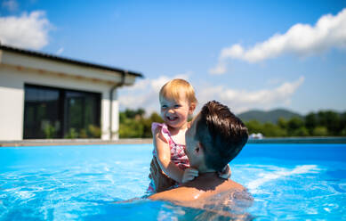 Junger Vater mit kleiner Tochter im Schwimmbad im Hinterhof Garten, spielen. - HPIF17015
