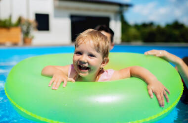 Glückliche junge Familie mit kleiner Tochter im Schwimmbad im Garten. - HPIF17021