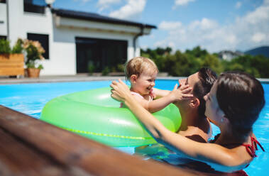 Glückliche junge Familie mit kleiner Tochter im Schwimmbad im Garten. - HPIF17022
