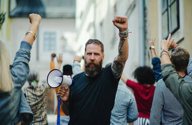 Frontansicht Porträt eines Mannes mit Megaphon, der auf der Straße protestiert, Streik- und Demonstrationskonzept. - HPIF17053