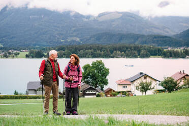 Ein älteres Rentnerpaar mit Nordic-Walking-Stöcken beim Wandern in der Natur, im Gespräch. - HPIF17144