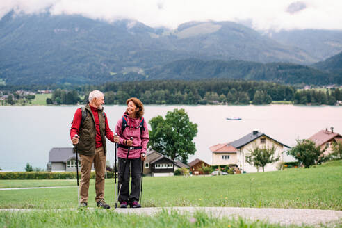 A senior pensioner couple with nordic walking poles hiking in nature, talking. - HPIF17144
