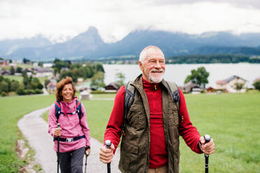 Ein älteres Rentnerpaar mit Nordic-Walking-Stöcken beim Wandern in der Natur, im Gespräch. - HPIF17146