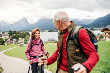 Ein älteres Rentnerpaar mit Nordic-Walking-Stöcken beim Wandern in der Natur, im Gespräch. - HPIF17147