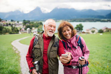 Ein älteres Rentnerpaar beim Wandern in der Natur, mit Smartphone. - HPIF17150