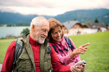 A senior pensioner couple hiking in nature, using smartphone. - HPIF17151