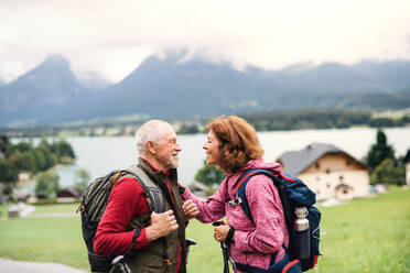 Ein älteres Rentnerpaar mit Nordic-Walking-Stöcken beim Wandern in der Natur, im Gespräch. - HPIF17153