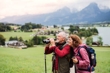 Ein älteres Rentnerpaar beim Wandern in der Natur, mit einem Fernglas. - HPIF17155