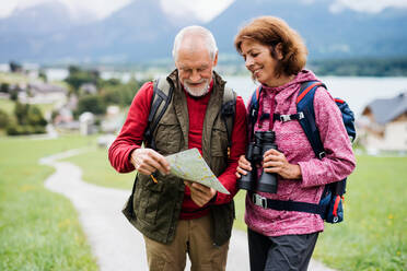 Ein älteres Rentnerpaar beim Wandern in der Natur, mit Fernglas und Karte. - HPIF17158