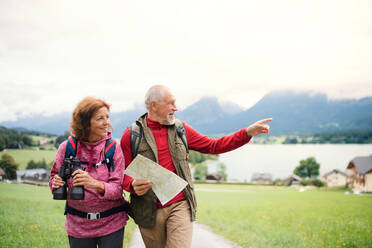 A senior pensioner couple with hiking in nature, using binoculars and map. - HPIF17159