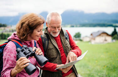 Ein älteres Rentnerpaar beim Wandern in der Natur, mit Fernglas und Karte. - HPIF17160