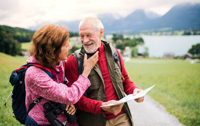 A senior pensioner couple with hiking in nature, using binoculars and map. - HPIF17161