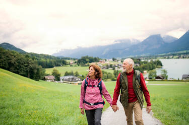 Frontansicht eines aktiven Rentnerpaares beim Wandern in der Natur, das sich an den Händen hält. - HPIF17164