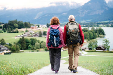 Rückansicht eines aktiven Rentnerpaares beim Wandern in der Natur, das sich an den Händen hält. - HPIF17165