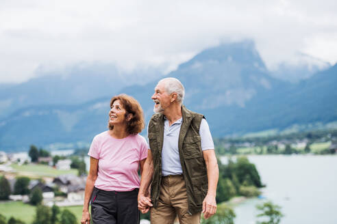 An active senior pensioner couple hiking in nature, holding hands. - HPIF17171