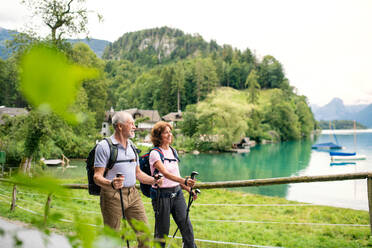 Ein glückliches Rentnerpaar mit Nordic-Walking-Stöcken beim Wandern in der Natur. - HPIF17173