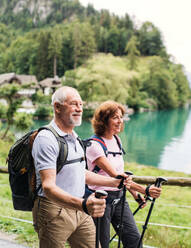 Ein glückliches Rentnerpaar mit Nordic-Walking-Stöcken beim Wandern in der Natur. - HPIF17174