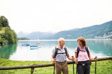 A happy senior pensioner couple with nordic walking poles hiking in nature, resting. - HPIF17176