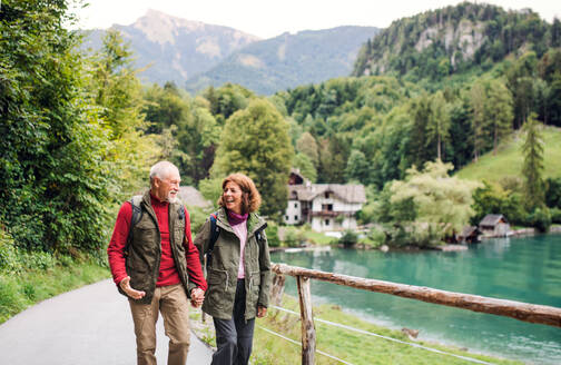 An active senior pensioner couple hiking in nature, holding hands. - HPIF17202