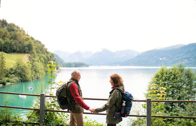 Ein älteres Rentnerpaar, das in der Natur am See steht und sich unterhält. - HPIF17204