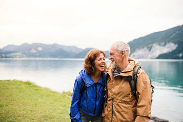 Ein älteres Rentnerpaar, das in der Natur am See spazieren geht und sich unterhält. - HPIF17208