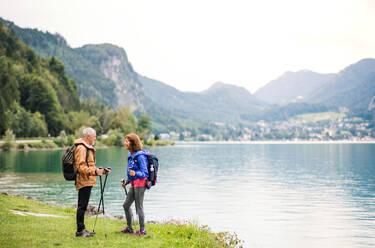 Ein älteres Rentnerpaar, das in der Natur am See steht und sich unterhält. - HPIF17209