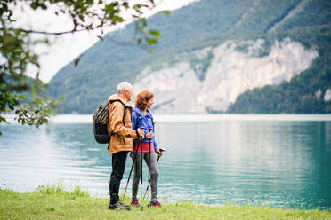 Ein älteres Rentnerpaar, das in der Natur am See steht und sich unterhält. - HPIF17210