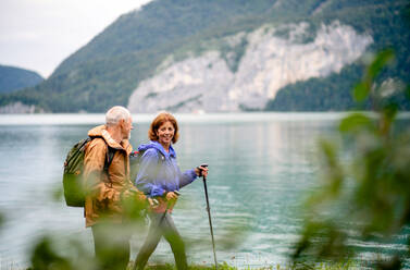Ein älteres Rentnerpaar wandert am See in der Natur und unterhält sich. - HPIF17212