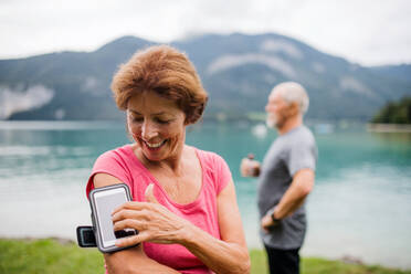 Senior Rentner Paar Läufer mit Smartphone am See in der Natur, ausruhen. - HPIF17226