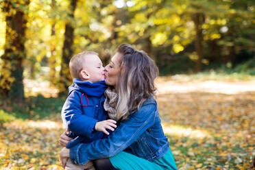 Schöne junge Mutter mit kleinem Kleinkind Sohn auf einem Spaziergang im Herbst Wald, küssen. - HPIF17259