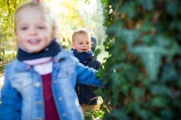 Glückliche Zwillinge Kleinkind Geschwister Junge und Mädchen mit Eltern auf einen Spaziergang im Herbst Wald. - HPIF17265