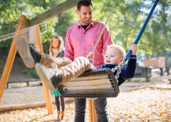 Eine schöne junge Familie mit kleinem Sohn spielt auf einem Spielplatz im Herbst. - HPIF17278