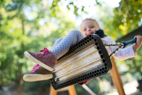 Ein kleiner Blickwinkel auf ein kleines Mädchen auf einer Schaukel auf einem Spielplatz. - HPIF17280