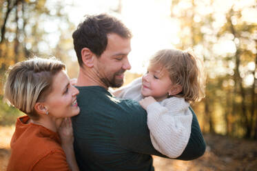 Beautiful young family with small daughter on a walk in autumn forest, talking. - HPIF17289