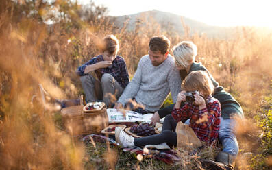 Schöne junge Familie mit kleinen Kindern beim Picknick in der herbstlichen Natur, sitzend im Gras. - HPIF17291