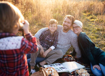 Schöne junge Familie mit kleinen Kindern beim Picknick in der herbstlichen Natur, beim Fotografieren. - HPIF17292