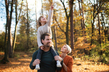 Beautiful young family with small daughter on a walk in autumn forest, having fun. - HPIF17321