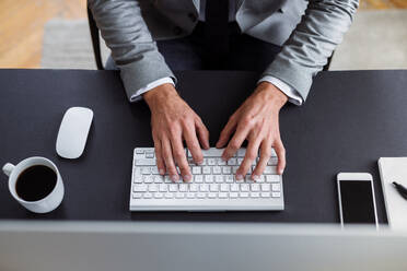 Ein Geschäftsmann mit Computer, der in einem Büro am Schreibtisch sitzt und arbeitet, von oben gesehen. - HPIF17378