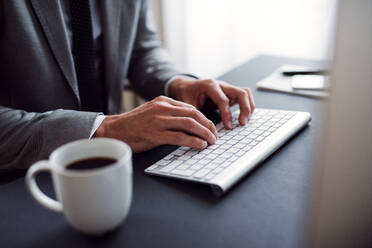 Ein Mittelteil des Geschäftsmannes mit Computer sitzt am Schreibtisch in einem Büro, arbeiten. - HPIF17389