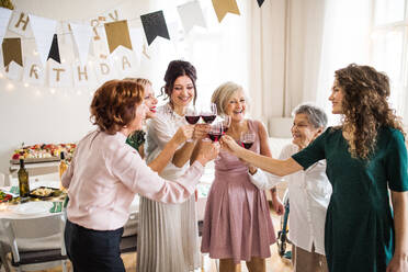 Eine Mehr-Generationen-Familie stößt auf einem Familiengeburtstag im Haus mit Rotwein an. - HPIF17446