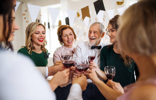 Eine Mehr-Generationen-Familie stößt auf einem Familiengeburtstag im Haus mit Rotwein an. - HPIF17449
