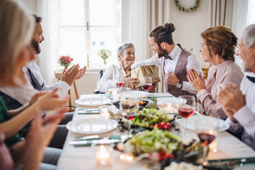 Eine ältere Großmutter im Rollstuhl, die mit ihrer Familie Geburtstag feiert, ein Partykonzept. - HPIF17459