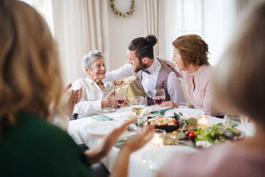 An elderly grandmother celebrating birthday with family and recieving a gift box, a party concept. - HPIF17460