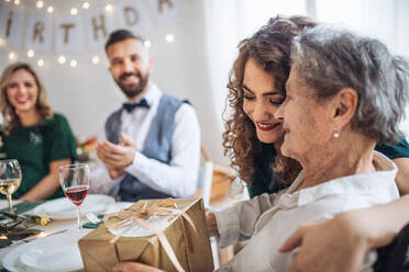 Eine ältere Großmutter feiert ihren Geburtstag mit ihrer Familie und erhält ein Geschenkpaket, ein Partykonzept. - HPIF17463