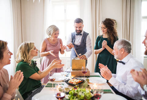 Ein glücklicher reifer Mann mit Freunden und Familie beim Öffnen von Geschenken auf einer Geburtstagsparty. - HPIF17484