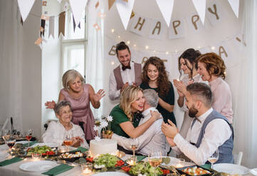 Ein älterer Mann mit einer Mehrgenerationenfamilie und einer Torte feiert seinen Geburtstag auf einer Indoor-Party. - HPIF17513